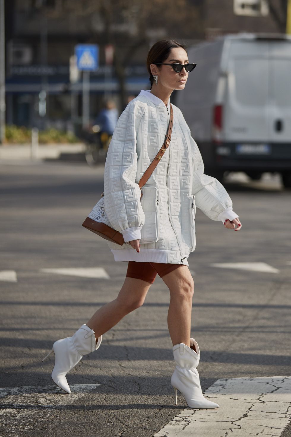 Mulher usando um look com bota branca composto por uma blusa branca oversized e shorts tipo academia