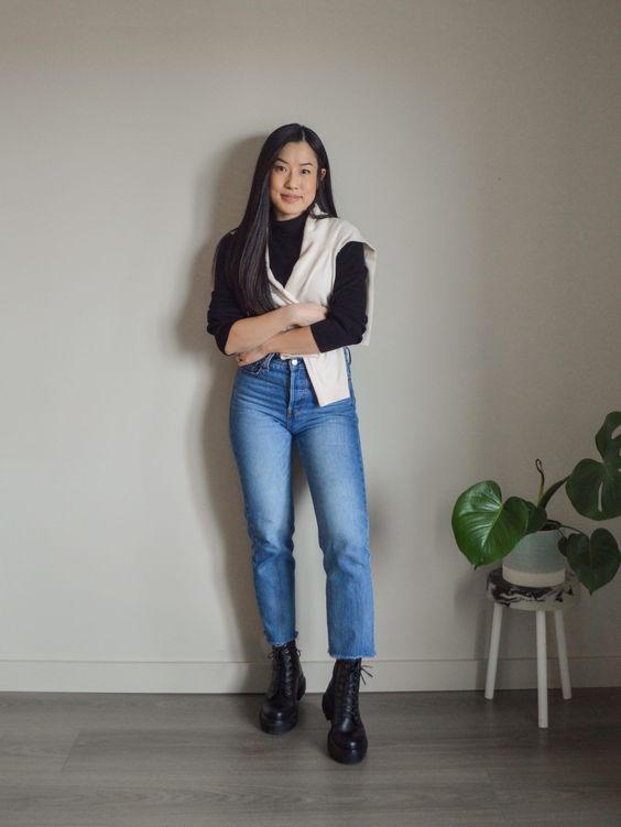 Mulher asiática usando um look com coturno composto por calça jeans e blusa de manga longa na cor preta
