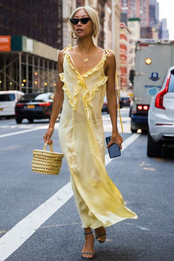 Mulher de traços asiáticos usando um look com sandália colorida predominantemente amarelo claro