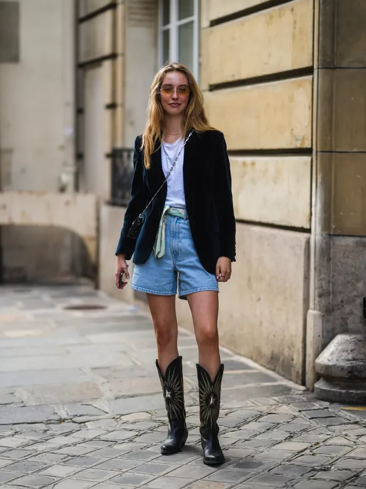 Mulher de óculos de lentes coloridas dando um exemplo despojado de como usar bota texana bordada ou detalhada