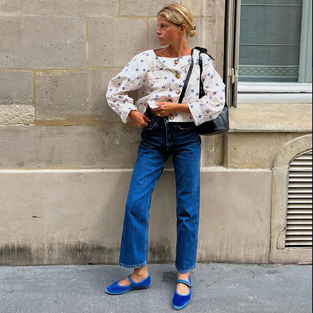 Mulher loira usando um look com sapato boneca de cor azul, blusa com pequenas estampas e jeans reta
