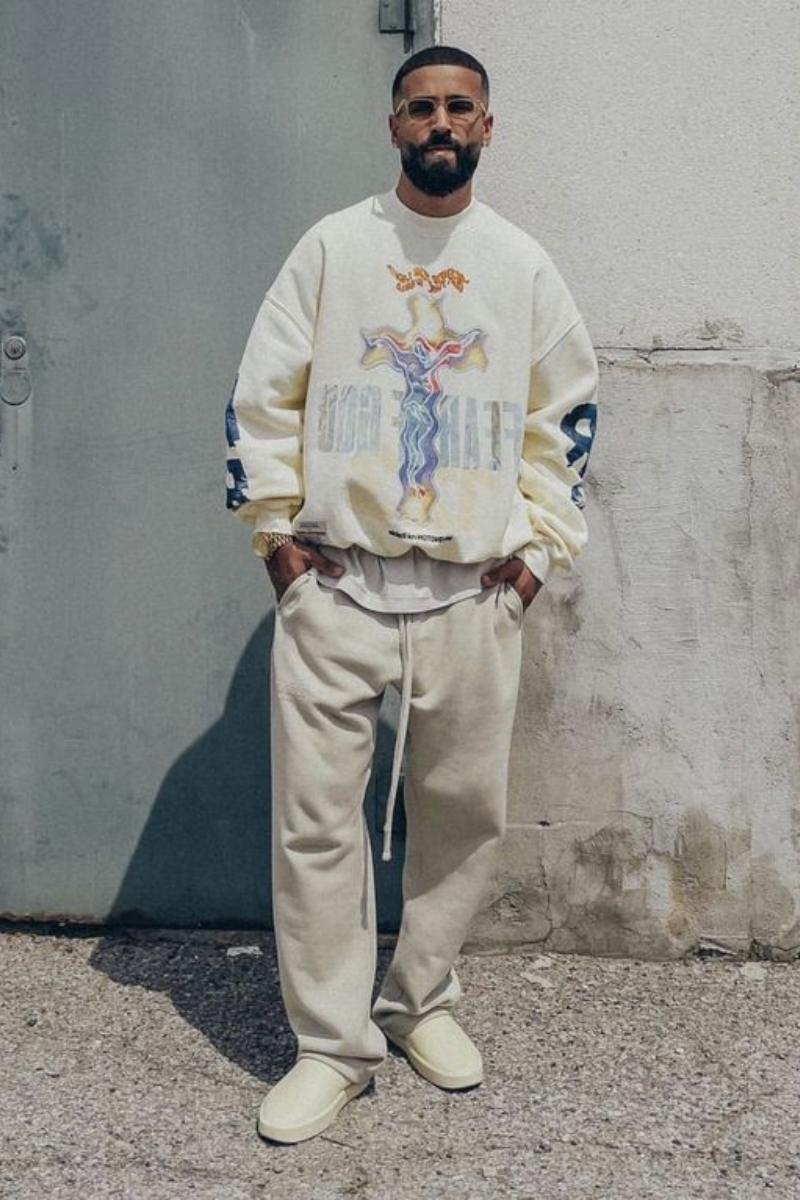 Homem usando um look estilo streetwear composto por um moletom de cores claras