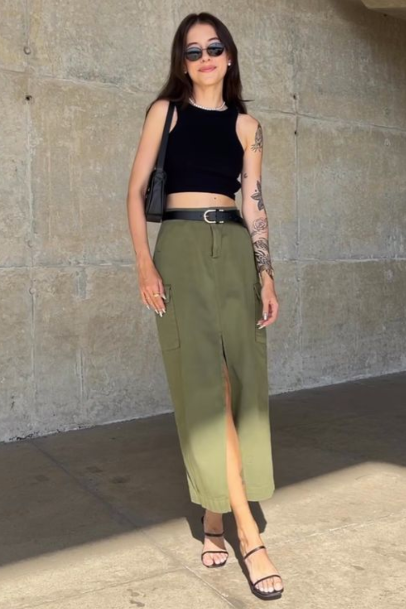 Mulher usando um look estilo streetwear com saia cargo de cor oliva e blusa cropped preta