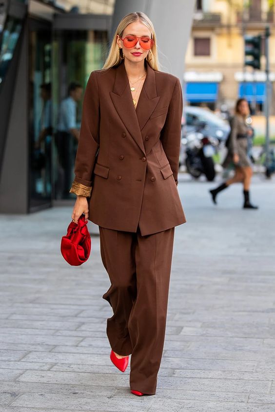Mulher loira usando um look outono predominantemente marrom com peças de alfaiataria