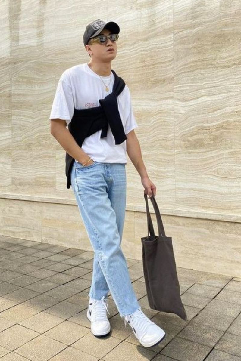 Homem usando um look casual masculino composto por camiseta branca e jeans de lavagem clara.