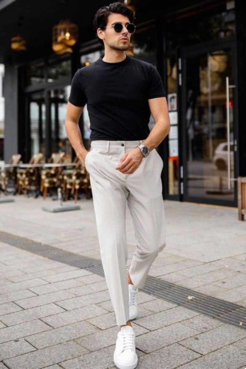 Homem branco usando um look casual masculino usando calça de alfaiataria clara e camiseta básica preta