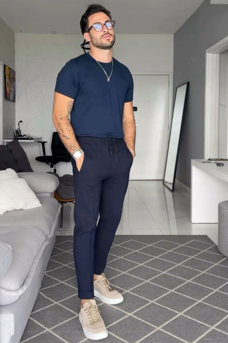 Homem usando um look casual masculino predominantemente azul escuro composto por camiseta básica e calça de aspecto social