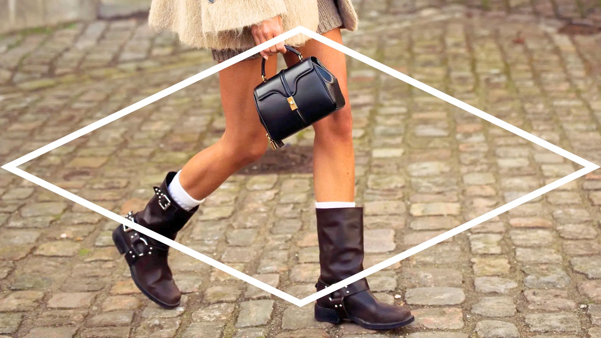 Pernas de uma mulher segurando uma bolsa de couro pequena e usando um modelo de bota de cano médio de cor marrom escura