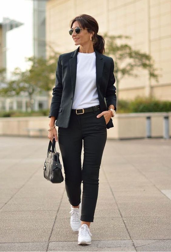 Mulher usando um look composto po blazer e calça jeans pretos e um par de tênis casual branco em um ótimo exemplo de presente dia das mães