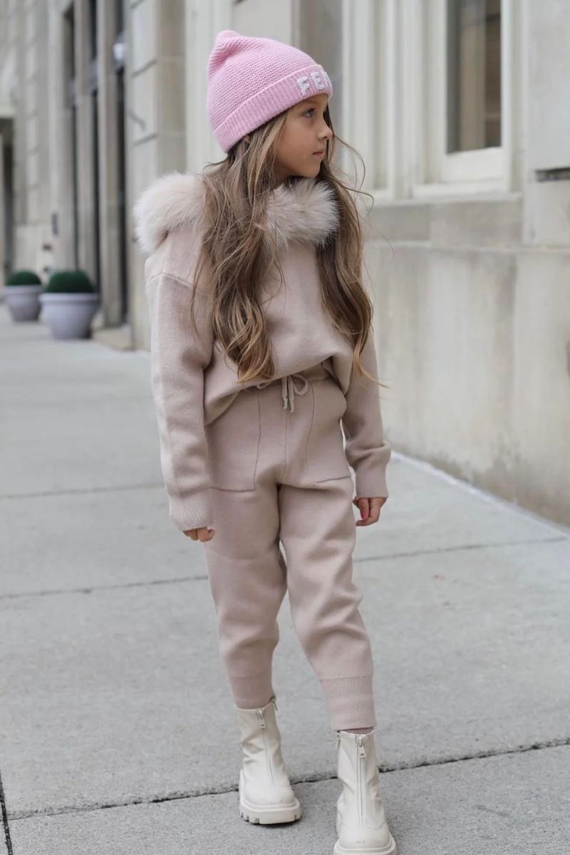 Menina de cabelos longos e lisos usando um look de inverno infantil feminino predominantemente rosa com touca