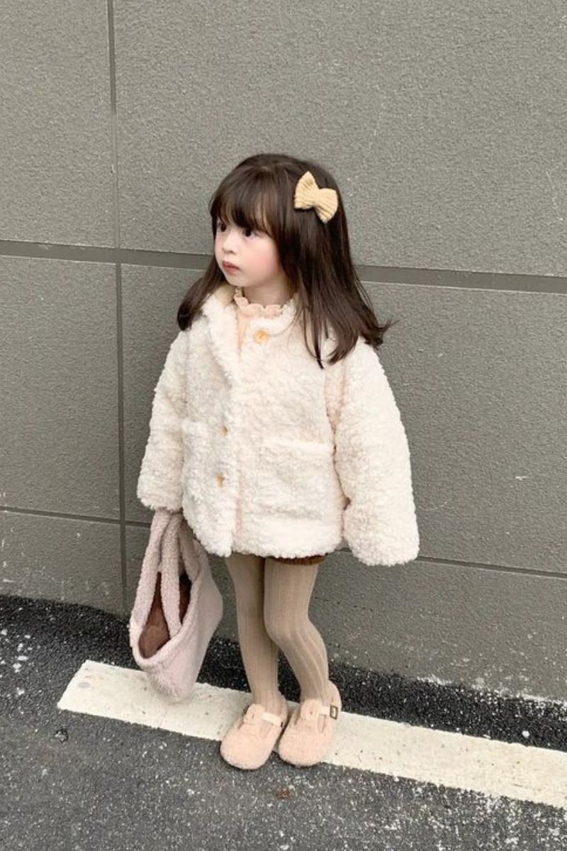 Menina pequena asiática usando um look de inverno infantil feminino com casaco teddy.