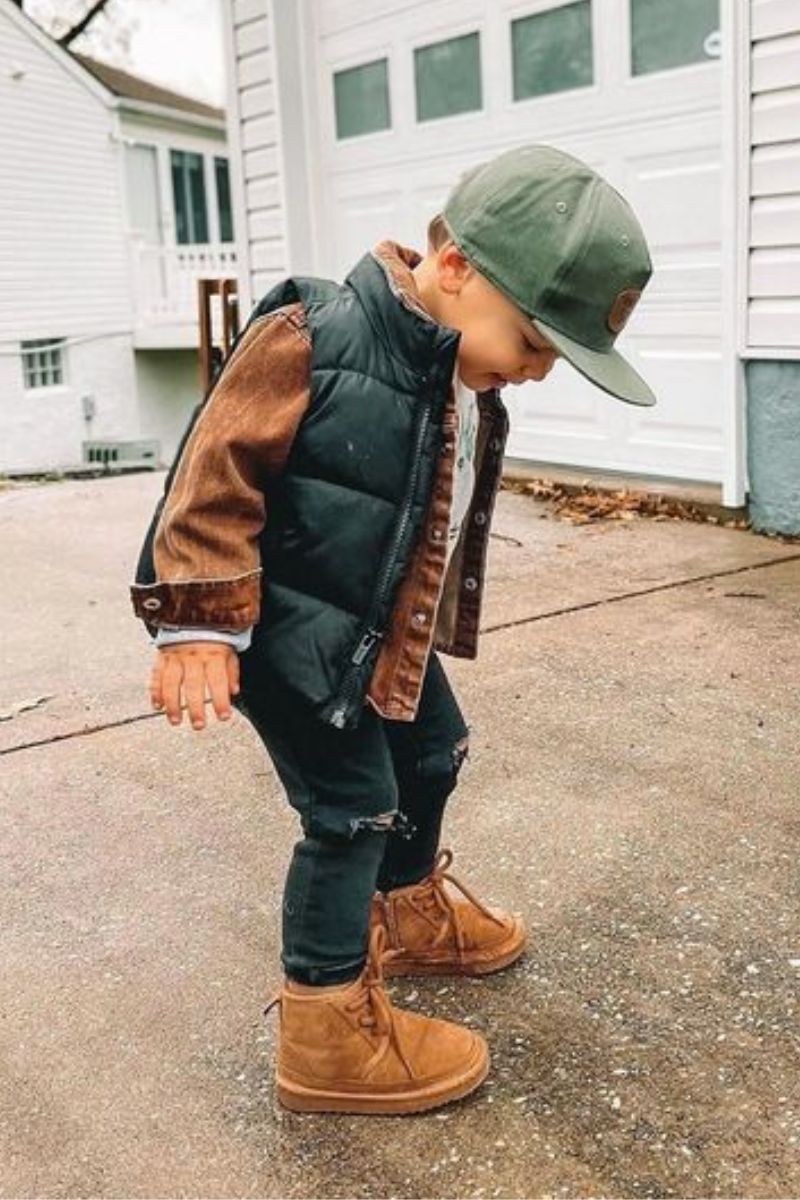 Menino branco pequeno usando um look infantil com bota composto por bota cano curto e colete puffer