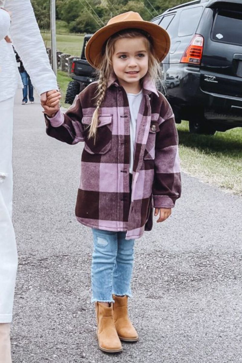 Menina de cabelo trançado usando um look infantil com bota cano curto e jeans