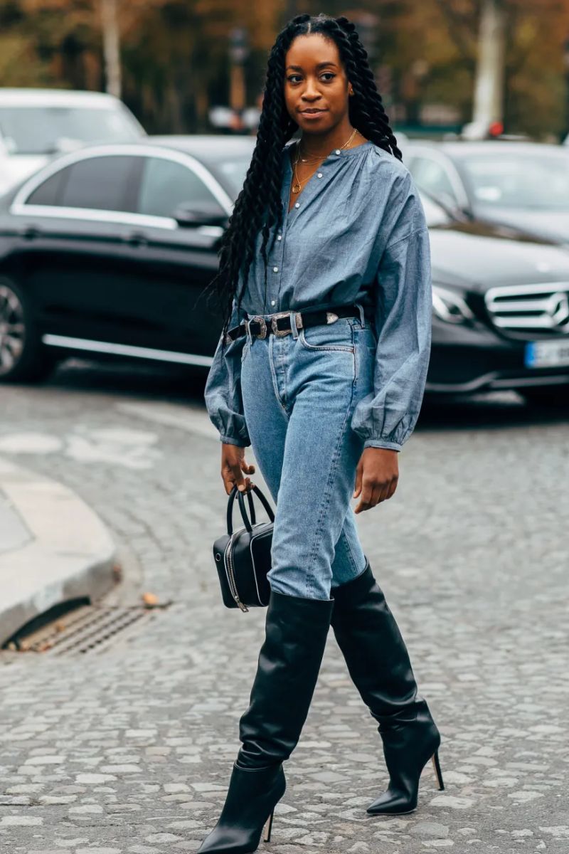 Mulher negra de cabelos longos dando um exemplo de como usar bota de cano longo com um look all jeans