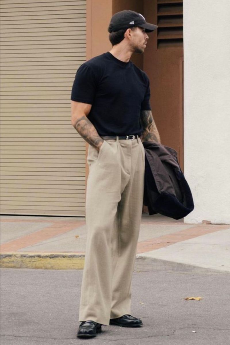 Homem usando um boné esportivo preto mostrando como usar mocassim masculino com calça pantalona