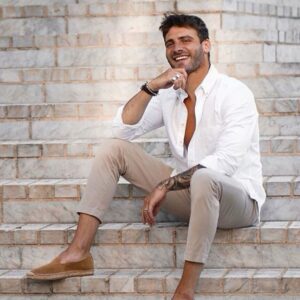 Homem sentado numa escada usando um tipo de calça masculina clara e justa