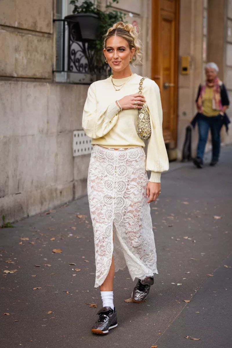 Mulher branca usando um look com saia de renda branca e tênis