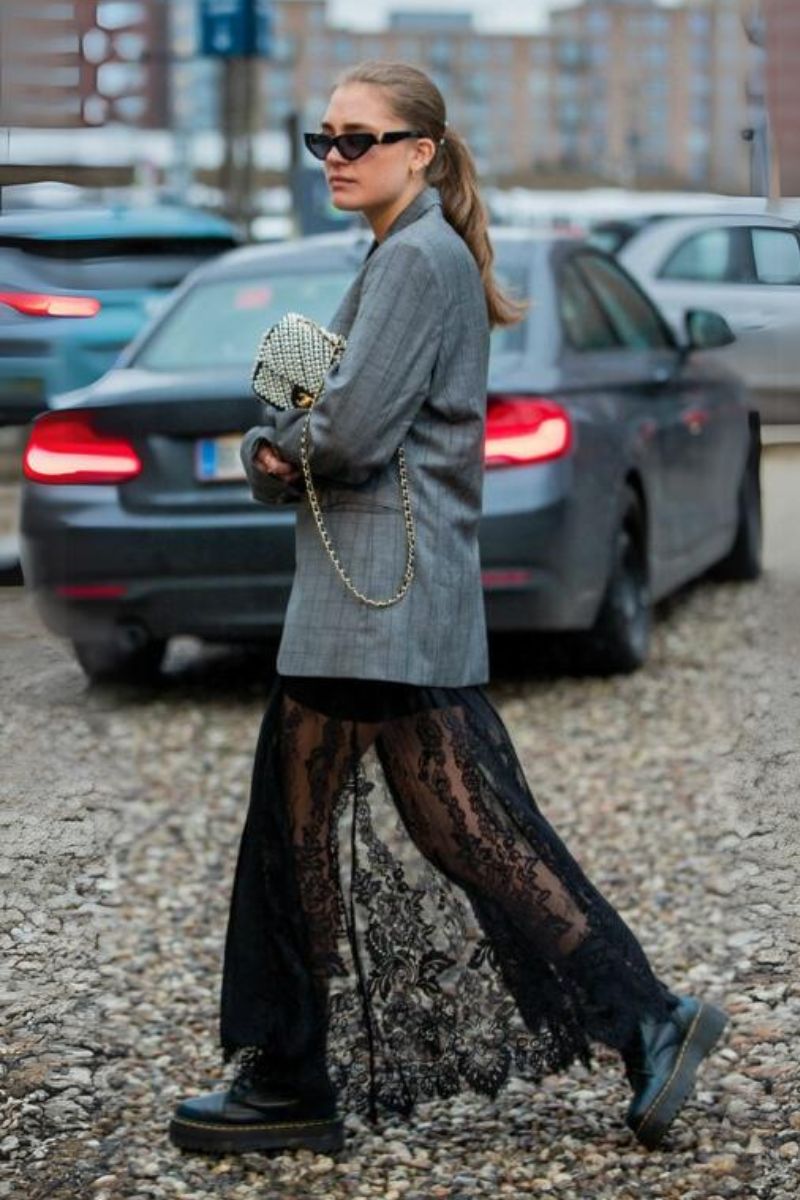 Mulher loira de cabelos presos usando um look com saia de renda preta