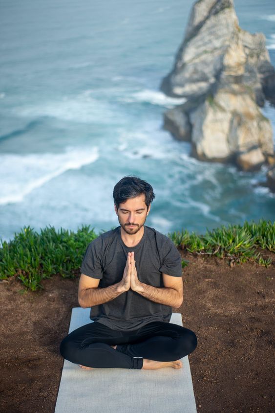 Imagem de um homem à beira-mar usando um look para academia masculino indicado para ioga