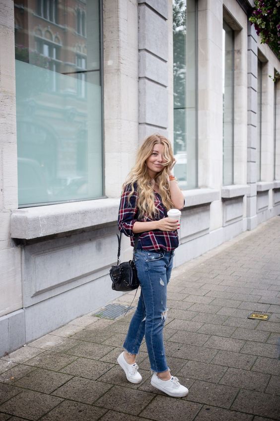 Mulher loira usando um look com tênis casual feminino branco, com jeans e camisa quadriculada