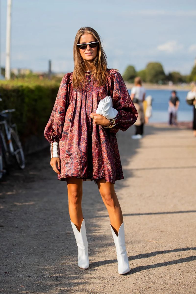 Mulher loira de cabelos soltos e dando um exemplo de o que é estilo boho com bota western