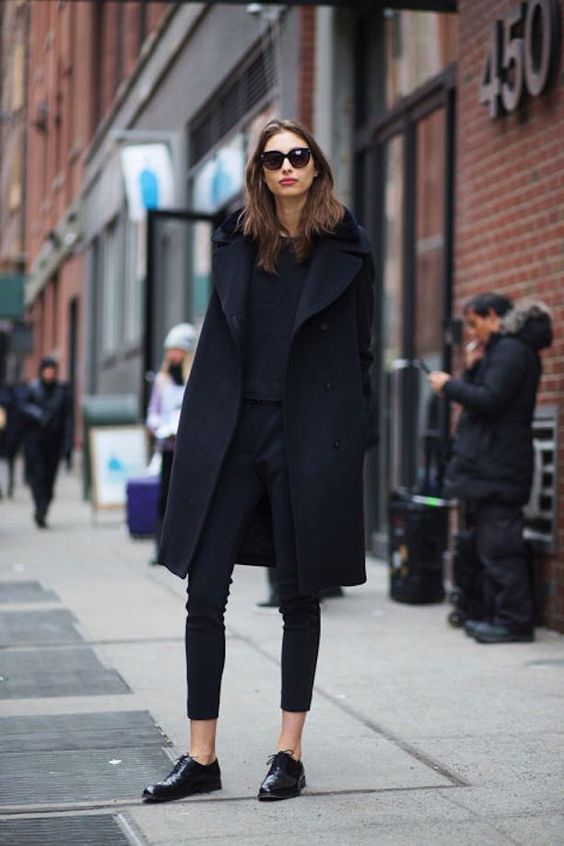 Mulher branca usando um look monocromático preto demonstrando como usar sapato verniz feminino