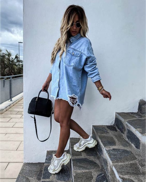 Mulher loira usando um look feminino com camisa masculina e dad sneakers