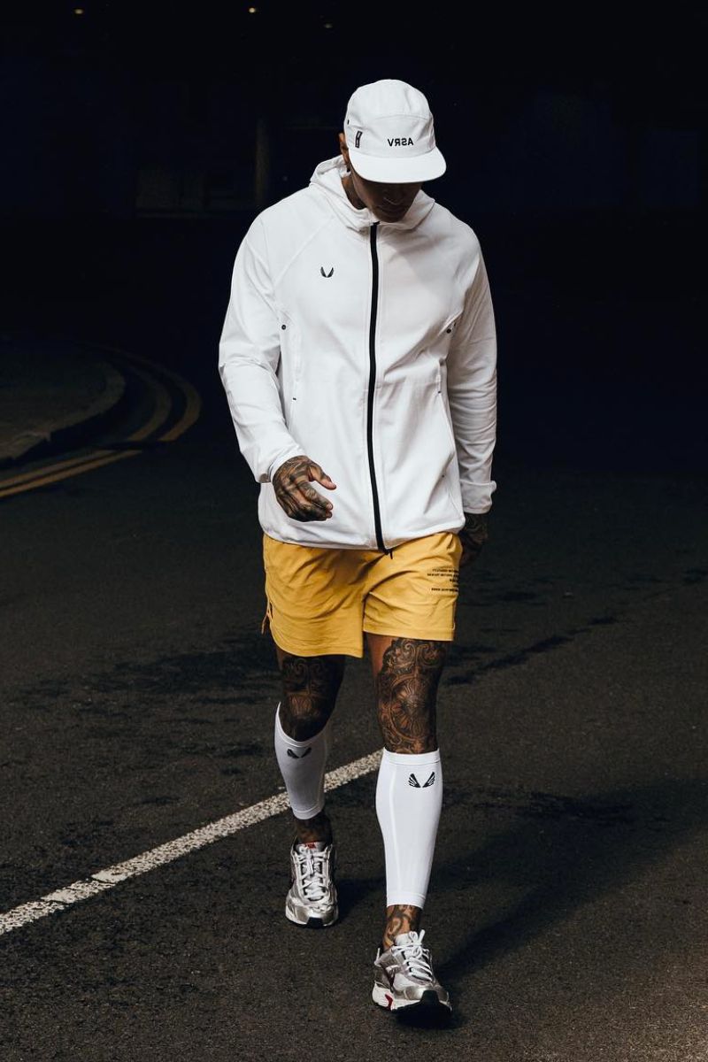 Homem negro usando um look para caminhada comporto por jaqueta e shorts esportivos amarelo