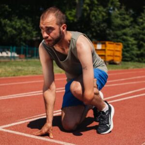 Homem prestes a correr numa pista de atletismo usando um dos melhores tênis para corrida masculino com amortecimento