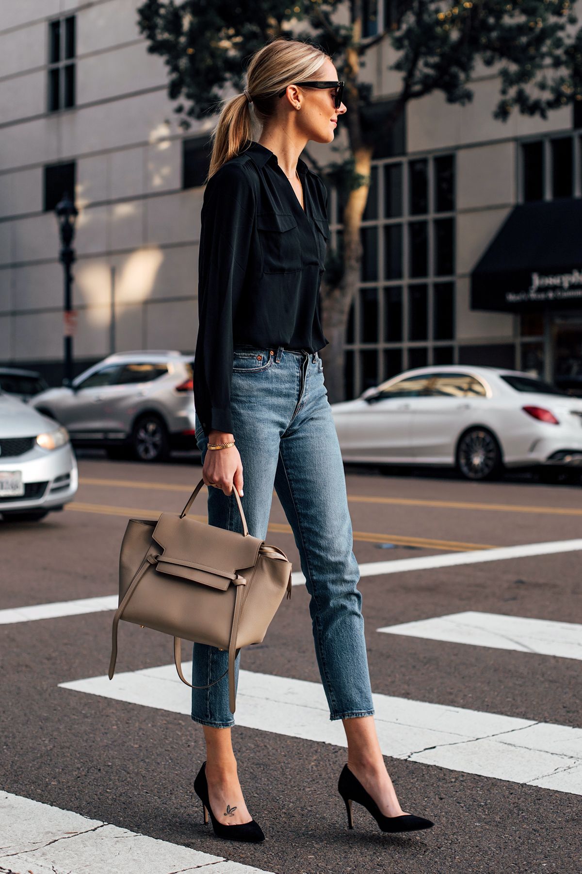 Mulher loira de cabelos lisos e presos usando um office look e mostrando quais são os tipos de sapatos sociais femininos a serem usados em eventos corporativos