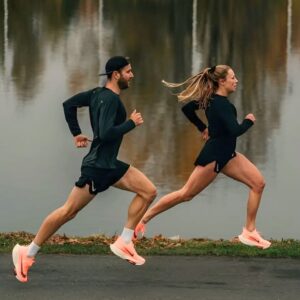 Homem e mulher correndo à beira de um lago usando um dos melhores tênis de corrida da atualizada da marca Nike