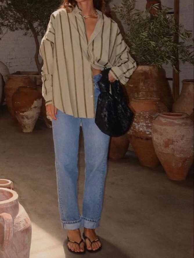 Mulher usando look com calça jeans, camisa listrada e chinelo para ilustrar quem inventou o chinelo.