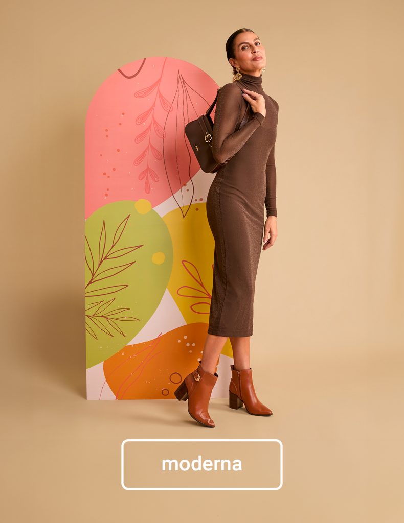 Mulher com look moderno e elegante, usando vestido marrom, bota de salto e bolsa no ombro — sugestão sofisticada de presente de Dia das Mães para mães estilosas.
